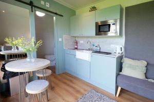 eine kleine Küche mit einem Waschbecken und einem Tisch mit Stühlen in der Unterkunft Ocean View 4 - 1 Bedroom Modern Pod - Llanrhidian in Llanrhidian