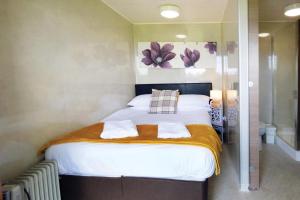 1 dormitorio con 1 cama con sábanas blancas y flores en la pared en Ocean View 8 - 1 Bedroom Chalet - Llanrhidian, en Llanrhidian