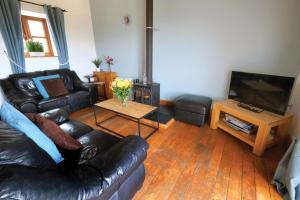 a living room with a leather couch and a television at Ocean View Cottage 2 - 2 Bed Cottage - Llanrhidian in Llanrhidian