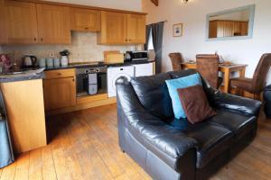 a living room with a leather couch in a kitchen at Ocean View Cottage 2 - 2 Bed Cottage - Llanrhidian in Llanrhidian