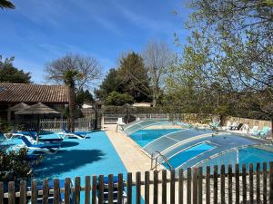 a swimming pool with chairs and a fence at Mobile home Premium 24m² 2 chambres in Arès