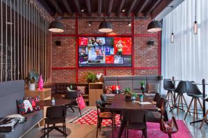 a restaurant with tables and chairs and a brick wall at Moxy Katowice Airport in Pyrzowice