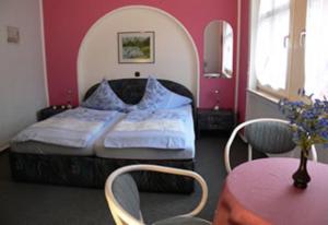 1 dormitorio con 1 cama, mesa y sillas en Pension-Elfi, en Maring-Noviand