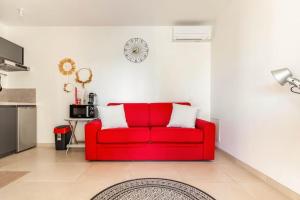- un canapé rouge dans le salon dans l'établissement Studio neuf avec acces piscine, à Valergues
