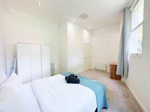 a bedroom with a white bed and a large window at Portobello Dock Canalside Apartment in London