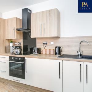 a kitchen with white cabinets and a stove top oven at Pluxa The Hideaway - Fully private serviced apartment & parking in Birmingham