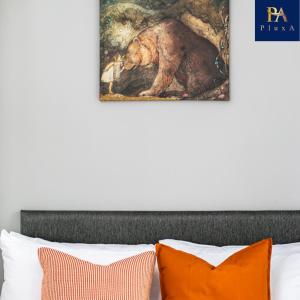 une peinture d'un ours au-dessus d'un lit avec des oreillers orange dans l'établissement Pluxa The Hideaway - Fully private serviced apartment & parking, à Birmingham