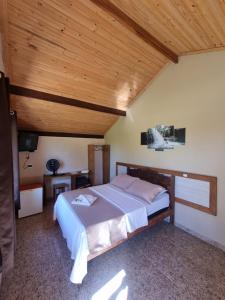 Chalés Encantos da Serra في كارانكاس: غرفة نوم بسرير وسقف خشبي