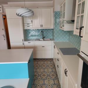 グディニャにあるSleepy3city Apartments Batorego 9の白いキャビネットと青いタイルのキッチン