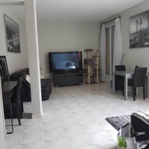 ein Wohnzimmer mit einem TV und einem Tisch mit Stühlen in der Unterkunft Duxplex aux Portes Monaco in Beausoleil