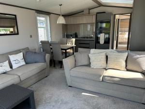 a living room with two couches and a kitchen at Mawgan Pads Lazy Days Lodge in Mawgan Porth
