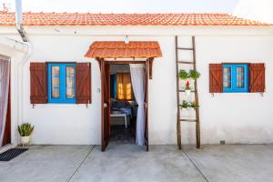 a white house with blue windows and a ladder at Bloomoon House in Bunheiro