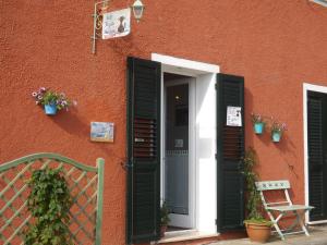 an orange building with a door and a bench and flowers at B&B Il Gatto Pescatore in Stintino