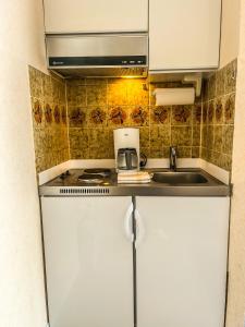 eine kleine Küche mit einer Spüle und einer Mikrowelle in der Unterkunft Haus Tida in Norderney