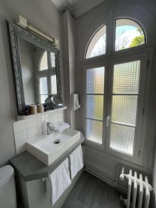 a bathroom with a sink and a mirror and a toilet at Hôtel Céline - Hôtel de la Gare in Rouen
