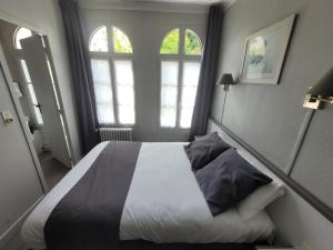 a bedroom with a large bed with two windows at Hôtel Céline - Hôtel de la Gare in Rouen