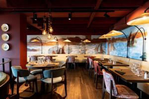 a restaurant with tables and chairs and a large mural at Hôtel Roz Marine Thalasso Resort in Perros-Guirec