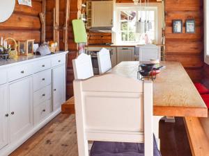 a kitchen with a wooden table and white cabinets at Holiday home HURDAL II in Hurdal