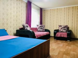 a bedroom with two chairs and a bed and a window at Apartaments in the city center in Karagandy