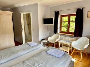 a bedroom with two beds and a television and chairs at Pension Steakhaus Füssen in Füssen