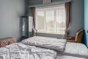 een bed in een slaapkamer met een raam en een stoel bij Hera 0101 in Koksijde
