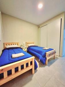 2 camas en una habitación con sábanas azules en Hermoso departamento en Mendoza en Godoy Cruz