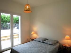 ein Schlafzimmer mit einem Bett und einem großen Fenster in der Unterkunft Maison spacieuse avec piscine sur le Bassin d'Arcachon in Lanton