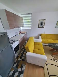 cocina con sofá amarillo y cocina con fogones en Apartman Benat en Stolac