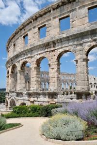 a large stone building with arches in a garden at La Dolce Vita Apartments in the city center with private parking in Pula