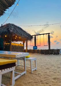 uma mesa de piquenique na praia com um guarda-sol de palha em Windy Waves Kite Beach & Nature Resort em Kalpitiya