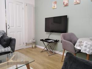 a living room with a flat screen tv and a table at cosy annex close to leeds airport in Guiseley