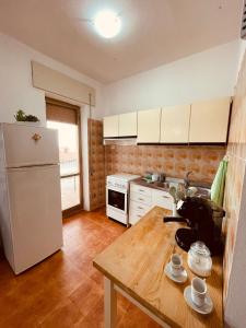cocina con mesa de madera y nevera blanca en Appartamento di Egidio, en San Pasquale