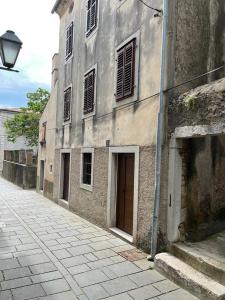 an old building with a door on the side of a street at Đana in Cres