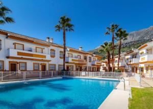 a swimming pool in front of a building with palm trees at Casas de Benaojan 15 in Benaoján