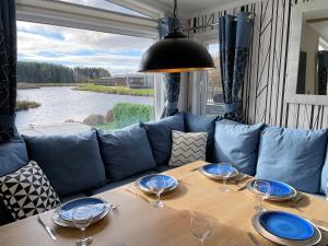 a table with plates and wine glasses on a couch at Luxury Lakeside Lodge with HTub Beautiful Views in Annan
