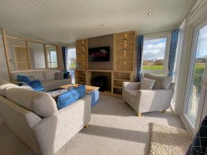 a living room with two couches and a tv at Luxury Lakeside Lodge with HTub Beautiful Views in Annan
