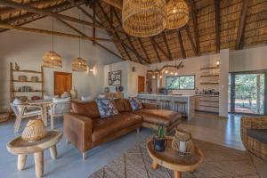 a living room with a couch and tables and a kitchen at Ukanyi Luxury Villa in Hoedspruit