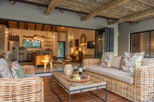 sala de estar con sofá, sillas y mesa en Ukanyi Luxury Villa en Hoedspruit