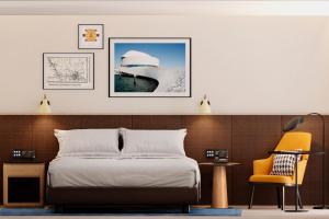 a bedroom with a bed and a yellow chair at Four Points by Sheraton Matosinhos in Matosinhos