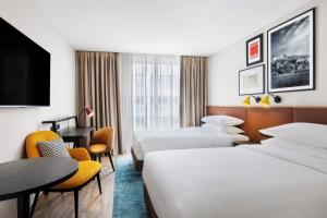 a hotel room with two beds and a desk at Four Points by Sheraton Matosinhos in Matosinhos