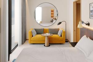 a living room with a yellow couch and a mirror at Four Points by Sheraton Matosinhos in Matosinhos