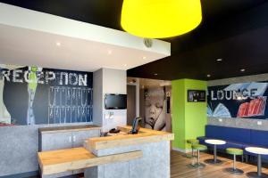 a lobby with a bar with stools and a television at ibis budget Clermont Ferrand Nord Riom in Riom