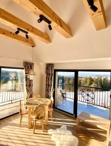 a living room with a table and a balcony at Domek Tatry - Stacja Wierchowa 972 m in Brzegi
