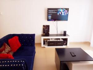 a living room with a blue couch and a tv at Homestay Luxurious apartments with swimming pool in Mtwapa
