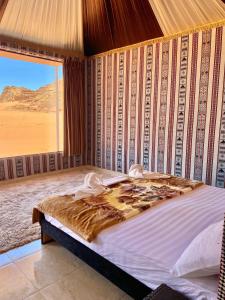 a bedroom with a large bed with a desert view at Rum Nights Bedouin Camp in Wadi Rum