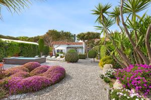 un jardín con plantas y flores púrpuras frente a un edificio en Villa Erika Beach House, en Malgrat de Mar