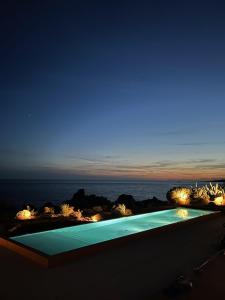 einen Pool mit Meerblick in der Nacht in der Unterkunft Hôtel Abbartello in Olmeto