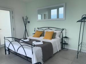 1 dormitorio con cama con almohadas amarillas y espejo en Top Lake View, en Faggeto Lario 