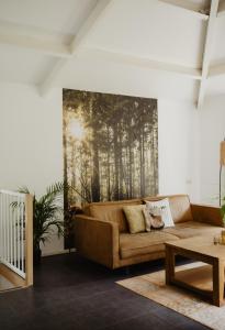 Una sala de estar con un sofá y un cuadro en la pared. en Bungalow Rondomzon, en Putten