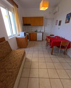 a kitchen and dining room with a red table and chairs at Monachus Monachus in Frangokastello